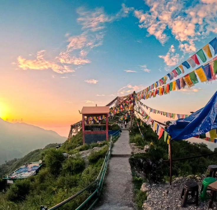 A breathtaking Himalayan sunset viewpoint adorned with colorful prayer flags, offering panoramic valley views and a serene spiritual atmosphere perfect for peaceful moments in the hills.