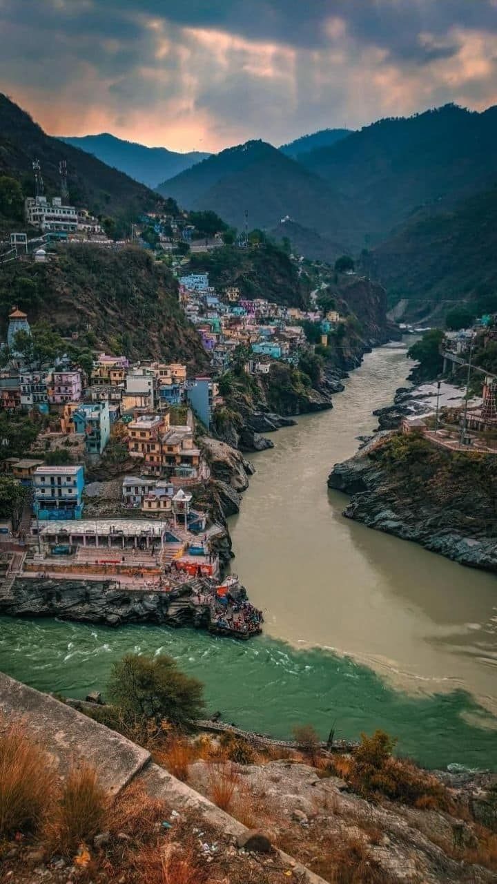 A stunning confluence of sacred rivers flowing through colorful hillside temples and ghats, capturing the spiritual heart and timeless beauty of Uttarakhand’s Himalayan towns.